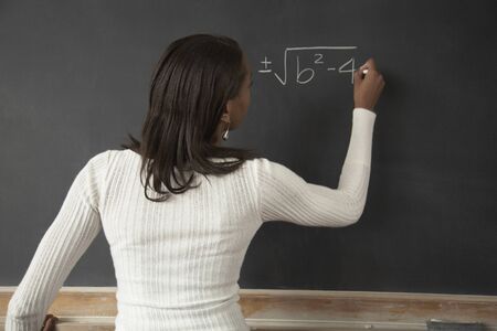African female student writing on blackboardの写真素材