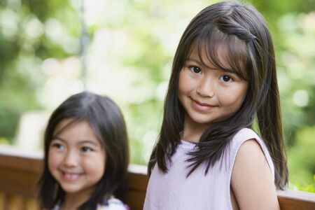 Young Asian sisters smiling outdoorsの写真素材