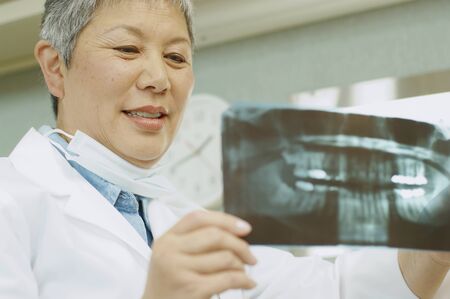 Senior Asian female dentist looking at x-raysの写真素材