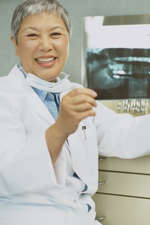 Senior Asian female dentist looking at x-raysの写真素材
