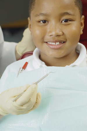 Close up of dentist's hand holding dental tool next to boy's mouthの写真素材