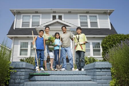 Hispanic family with gardening tools in front of houseの写真素材