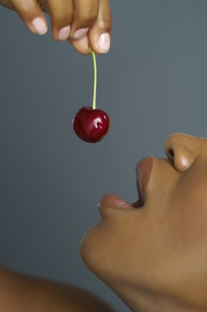 Close up of African woman eating cherryの写真素材