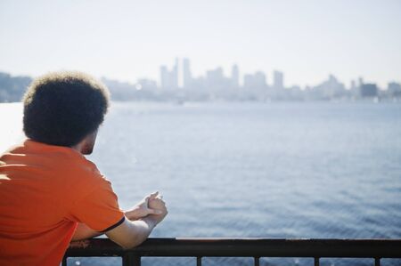 African man looking over water at city skylineの写真素材