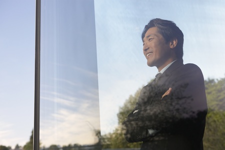Asian businessman looking through windowの写真素材