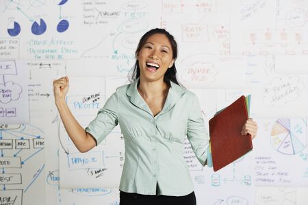 Asian businesswoman cheering in front of whiteboardの写真素材