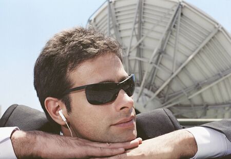 Hispanic man wearing earbuds next to satellite dishの写真素材