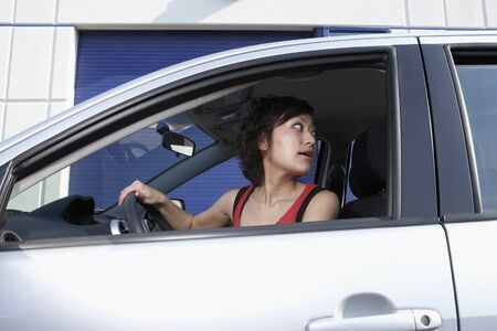 Asian woman looking over shoulder in carの写真素材