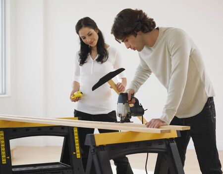 Hispanic couple drilling wood