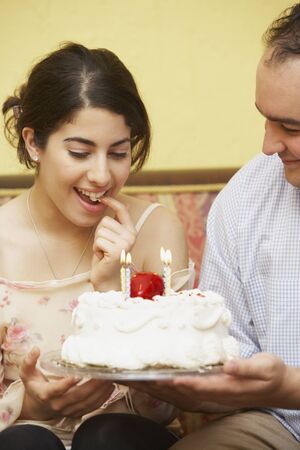 Hispanic man giving girlfriend birthday cakeの写真素材