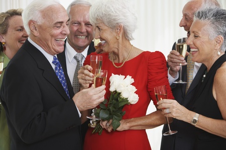 Senior friends drinking champagne at partyの写真素材