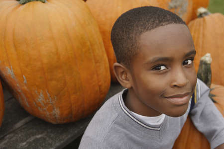 Portrait of African boy next to pumpkinsの写真素材