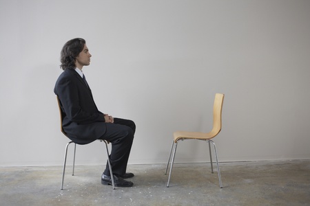 Businessman sitting across from empty chairの写真素材