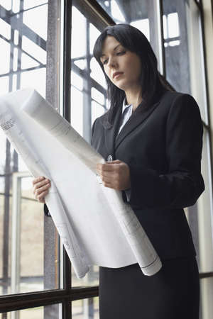 Businesswoman looking at blueprintsの写真素材