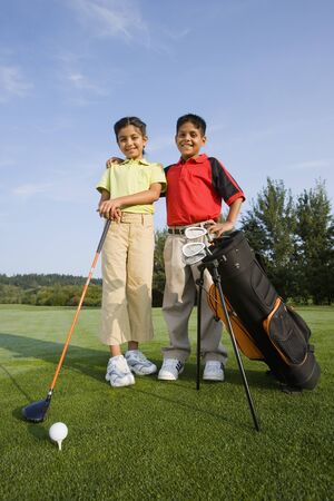 Hispanic brother and sister on golf courseの写真素材