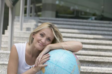 Young woman leaning on globeの写真素材