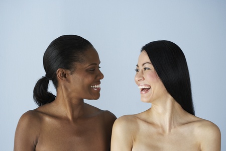 Two multi-ethnic women smiling at each otherの写真素材