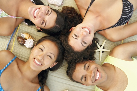 Multi-ethnic friends laying on beachの写真素材