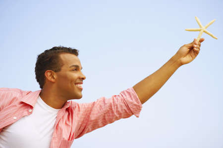 Hispanic man holding starfishの写真素材