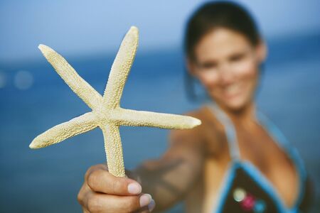 Woman holding up starfishの写真素材