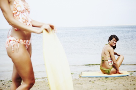 Young women with boogie boards at beachの写真素材