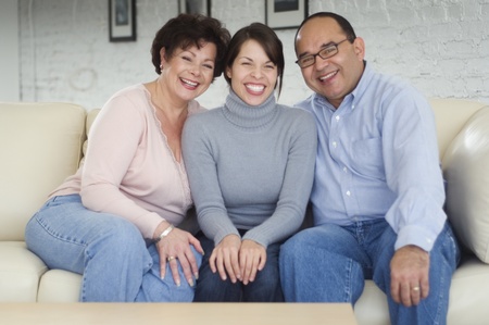 Hispanic parents and adult daughter on sofaの写真素材