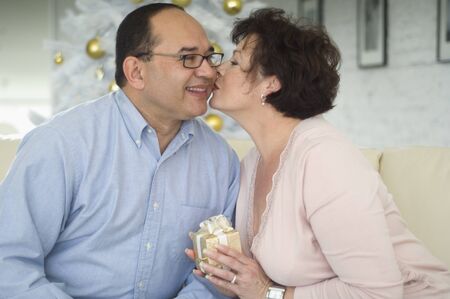 Hispanic woman kissing husband on Christmasの写真素材