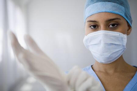 Female doctor putting on surgical glovesの写真素材