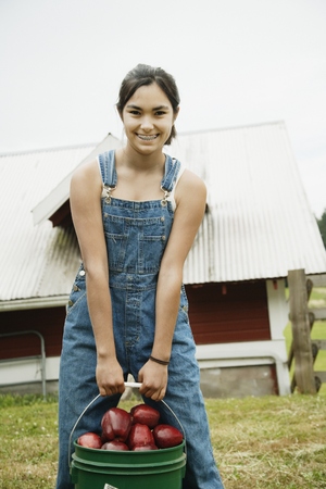 Girl carrying bucket of apples on farmの写真素材