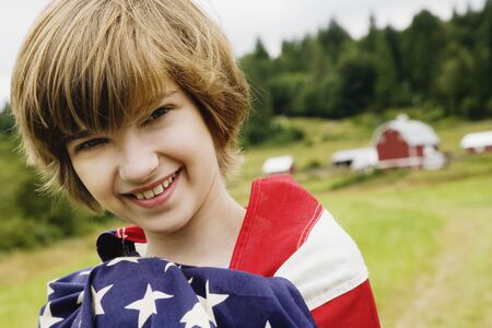 Girl wrapped in American flag on farmの写真素材