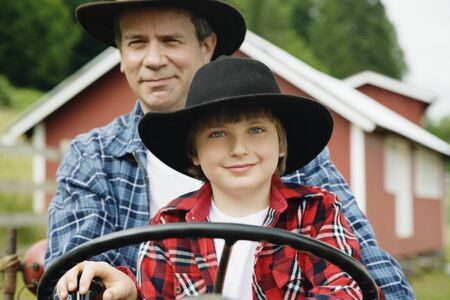 Father and son driving tractorの写真素材