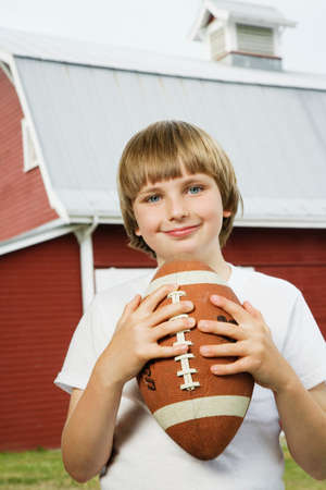 Boy holding football at farmの写真素材