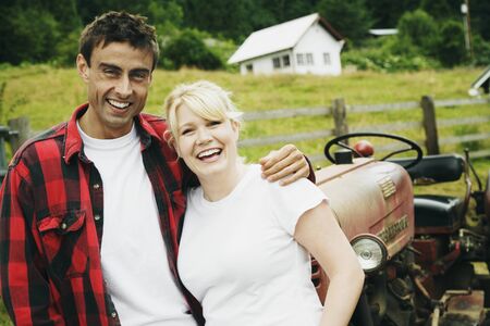 Couple standing in front of tractorの写真素材