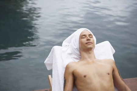 Man in lounge chair next to water