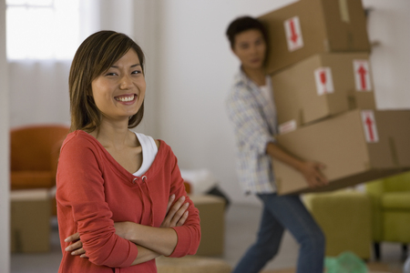 Asian woman laughing while husband carries boxesの写真素材