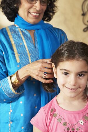 Indian grandmother fixing granddaughter's hair