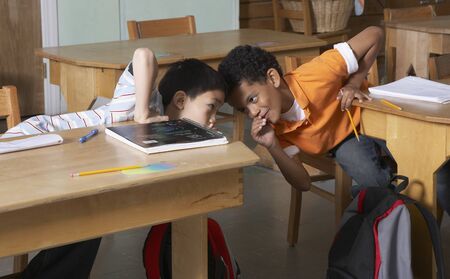 Multi-ethnic boys whispering in class