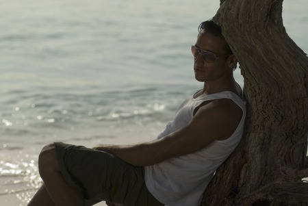 Hispanic man leaning against treeの写真素材