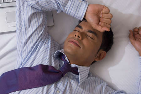 Hispanic businessman laying on bedの写真素材