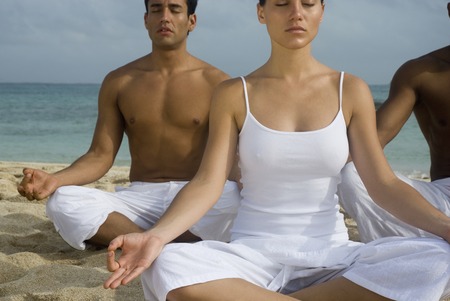 Multi-ethnic friends meditating on beachの写真素材