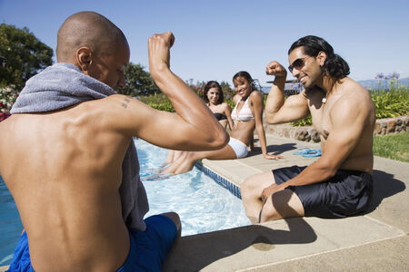 Multi-ethnic men flexing at swimming pool