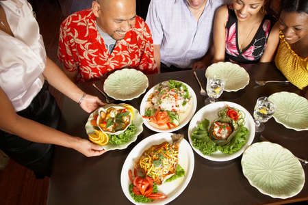 Multi-ethnic friends looking at table full of foodの写真素材