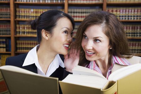Multi-ethnic women whispering in law library