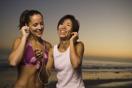 Multi-ethnic friends listening to same mp3 playerの写真素材