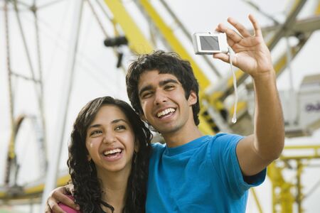 Ethnic-ethnic teenaged couple taking own photograph