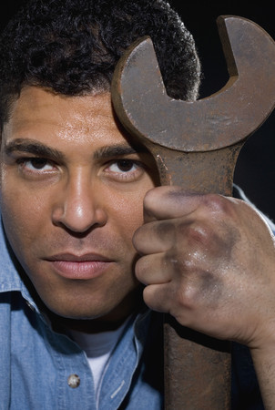 Hispanic man holding large wrenchの写真素材