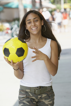 Mixed Race teenaged girl holding soccer ballの写真素材