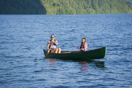 Asian mother and daughter rowing in canoeの写真素材