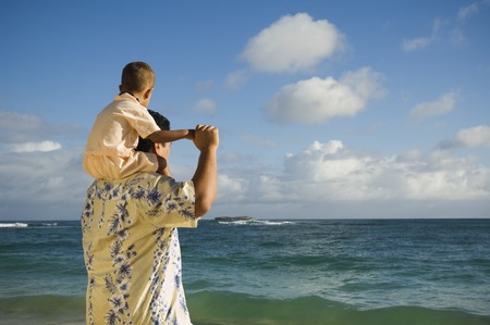 Pacific Islander father with son on shoulders at beachの写真素材