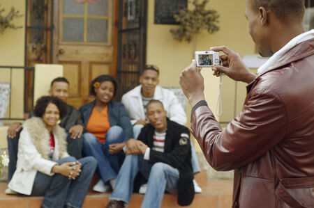 African man taking photograph of friendsの写真素材